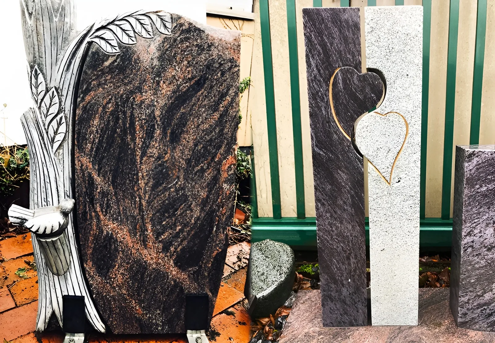 Zwei Grabmale in der Ausstellung: ein dunkler Granitstein mit hellem Baumrelief und Vogel sowie eine zweiteilige Stele aus dunklem und hellem Granit mit Herzmotiv
